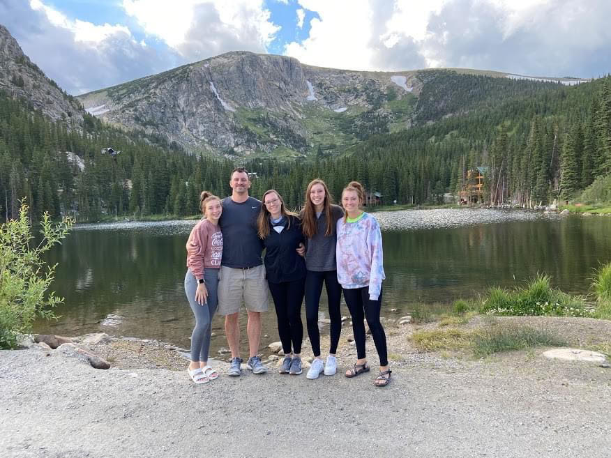 family smiling in front of a mountain and lake