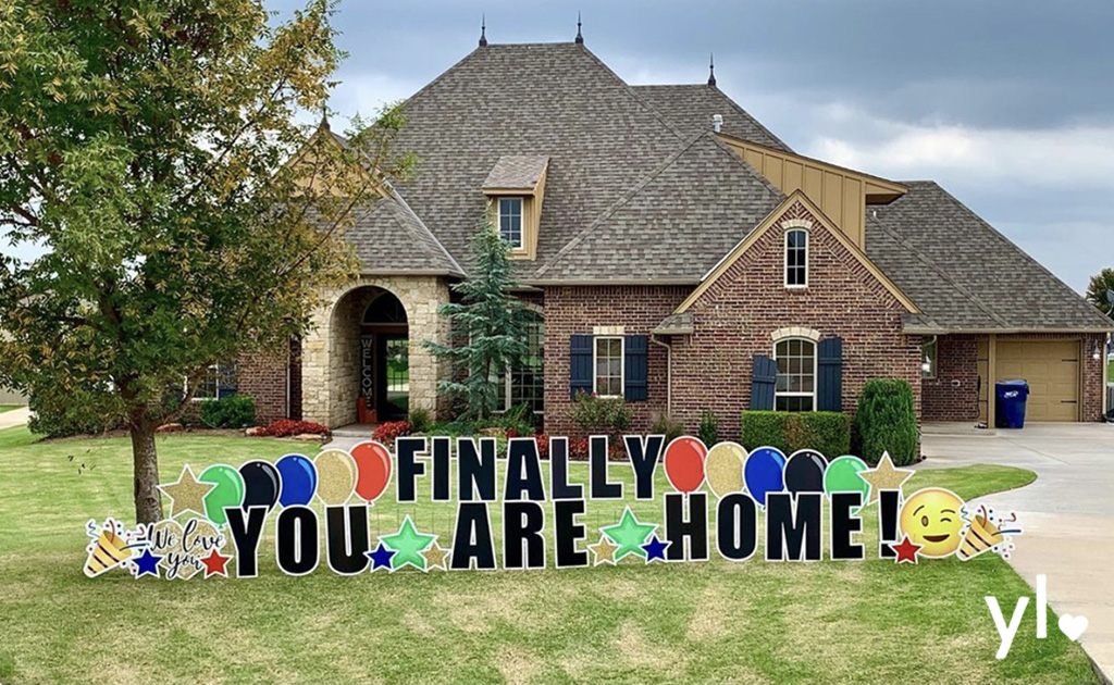 brick house with finally you. are. home! in black letters with primary color balloons and emojis