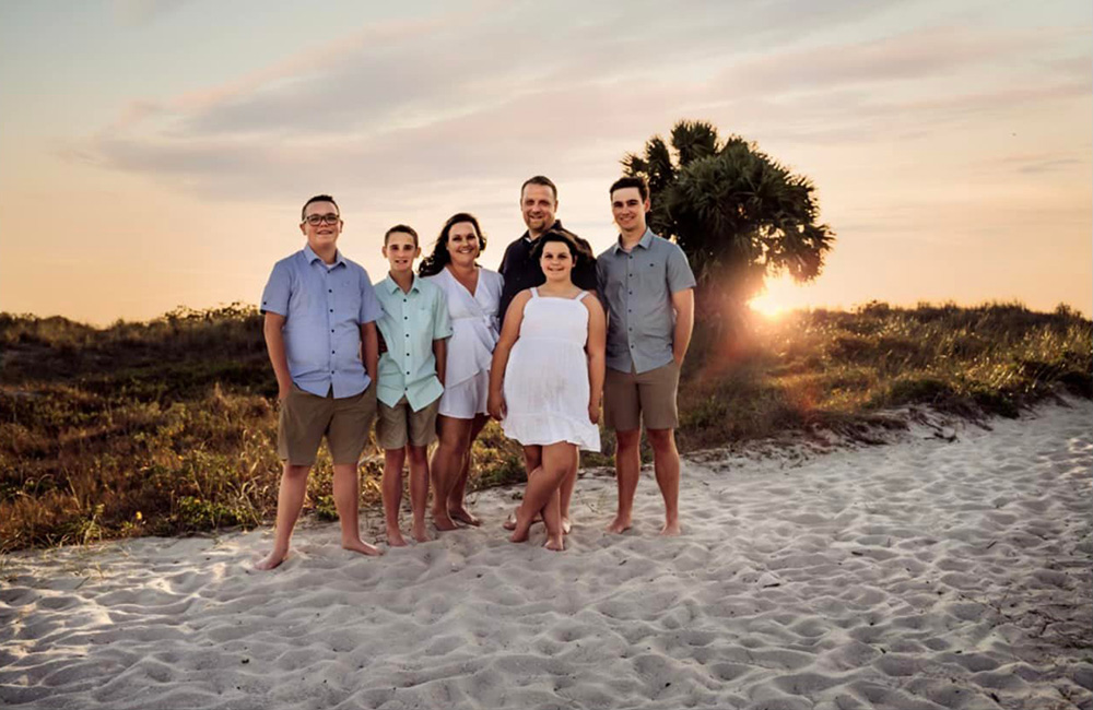Family on sand smiling for portrait at sunset